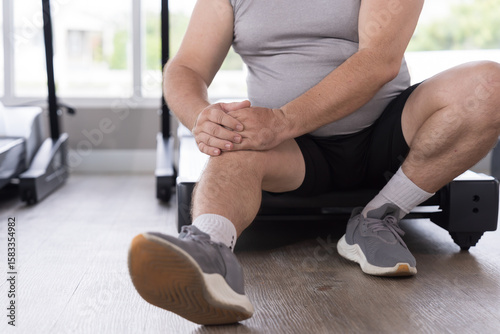 Exercise, knee pain, hands of man touching knee in gym. Male with injury after workout, training. Accident in gym. Knee injury at health club