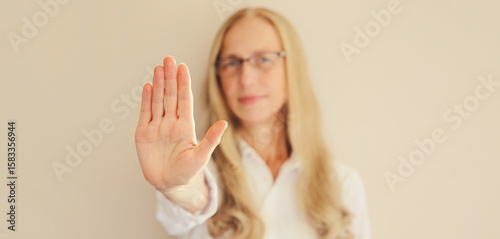 Woman shows stop, no or enough sign with palm of hand, refusal gesture, domestic violence