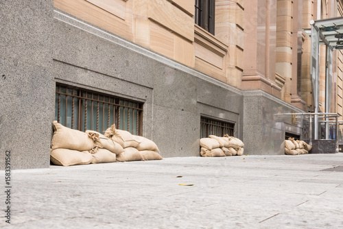 Sandbags along the footpath lining the lower windows of a building in Brisbane CBD before a cyclone