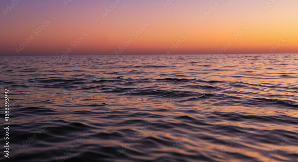 Obraz premium Calm ocean waters under pastel sunset sky at twilight 