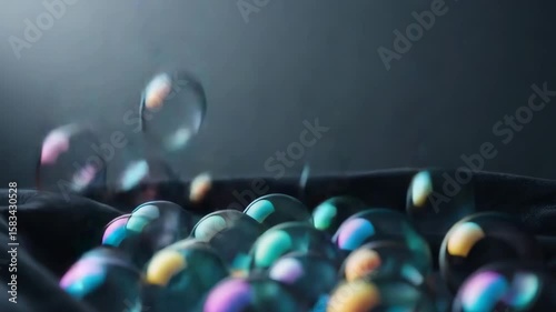 Experience the delicate dance of shimmering bubbles as they catch the light and move gracefully against a dark silky background