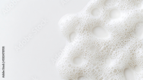 A close-up shot of white foam with varying bubble sizes, set against a clean white background. The texture evokes cleanliness and lightness. Minimalist aesthetic.