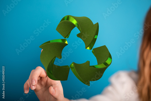 Fototapeta Naklejka Na Ścianę i Meble -  Woman interacts with a 3D recycling symbol.  Eco-friendly, sustainability, reuse.