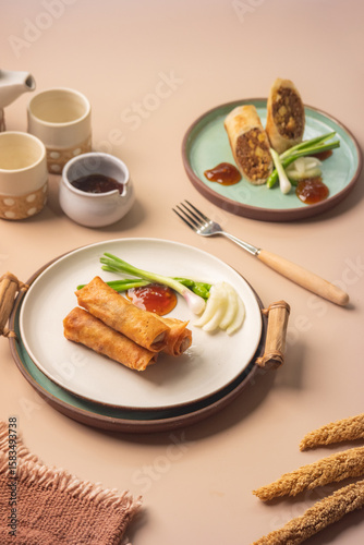 Top view of fried lumpia semarang spring rolls served with garnish and sauces. Suitable for menu design, cooking blog, or restaurant promotion