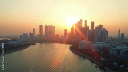 Wallpaper Mural A stunning sunset illuminates the skyline of a modern city, casting a golden glow on the buildings and the calm river that reflects the urban landscape and light. Torontodigital.ca