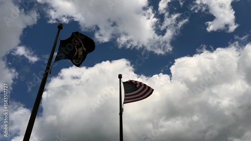 Michigan state flag and United States flag waving in the wind against blue sky with clouds 