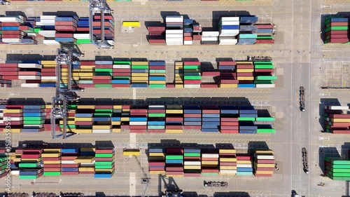 Top down aerial drone footage of shipping freight containers with heavy vehicles and cranes loading and unloading cargo shipping tankers in Felixstowe England UK