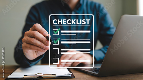 Completing task management with a checklist using pen on paper near laptop showcases project management, efficiency and meeting goals in the office environment.
