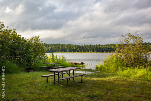 Wooden picnic tables at a grassy waterfront campsite near Temagami, Ontario, Canada