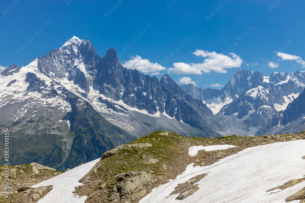 Fototapeta premium Beautiful mountain landscapes of the Alps on Tour du Montblanc hike. Green valley, snow summits and rocky peaks of Aiguilles de Chamonix and Montblanc. Summer sunny weather blue sky, trekking Alp hike