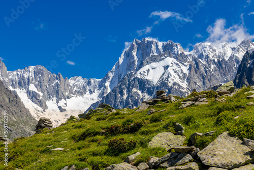 Beautiful mountain landscapes of the Alps on Tour du Montblanc hike. Green valley, snow summits and rocky peaks of Aiguilles de Chamonix and Montblanc. Summer sunny weather blue sky, trekking Alp hike