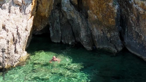 Beautiful Young Woman in Bikini Swims in Stara Baska Beach Krk Island, Croatia. Mediterranean Summer. Aerial Shot From Above. Blue Sea the Rocks  Mountains and Coastline Calm Sea With Clear Blue Water