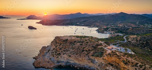 Fototapeta Naklejka Na Ścianę i Meble -  Panoramic aerial view of the bay at Cape Sounion, Greece, with the famous Temple of Poseidon, the beach and moored boats during summer sunset time