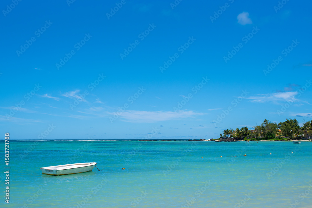 Beautiful landscape of Tropical Paradise - Belle Mare Beach with turquoise water. White boat in the Indian Ocean. Mauritius Island. Travel and vacation concept. Beautiful landscape of Tropical Paradise - Belle Mare Beach with turquoise water. White boat in the Indian Ocean. Mauritius Island. Travel and vacation concept.