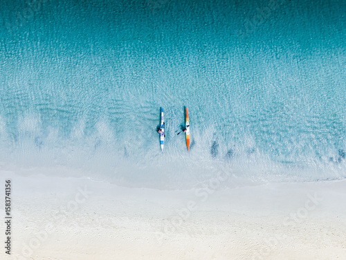 Aerial view of kayakers paddling through the crystalline turquoise water, a vibrant contrast to the soft, sandy beach, Western Australia, Western Australia, Australia.