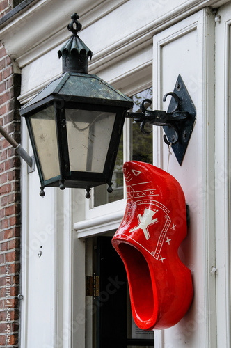 Canvas Print An oversized, red, wooden shoe hung as an ornament beside a street light outside the entrance to a residential building in Amsterdam, Holland, The Netherlands