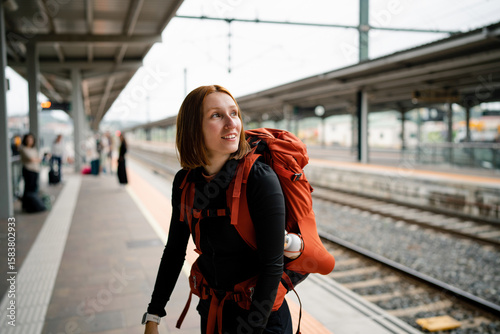 Young backpacker woman waiting for train at railway station