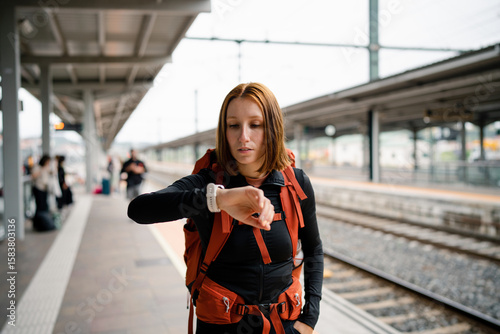 Young backpacker checking time at train station