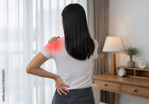 Woman experiencing sharp shoulder pain with a red inflamed area indicating discomfort and holding her lower back in a home setting