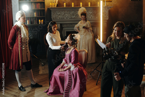 Foto Caucasian young adult woman sitting in ornate Baroque costume having makeup appl