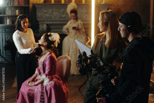 фотографія Caucasian young adult woman sitting in chair receiving makeup from another woman