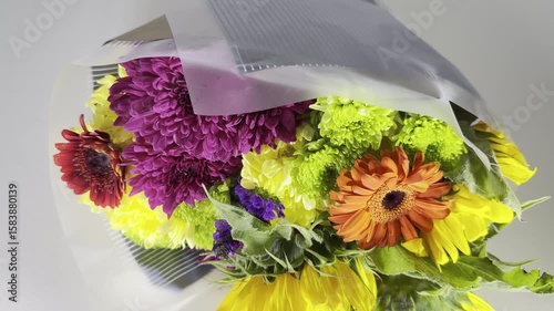 Closeup slow tilt shot of a bunch of isolated, vibrant, multi color flowers of various types, in gift wrapping.