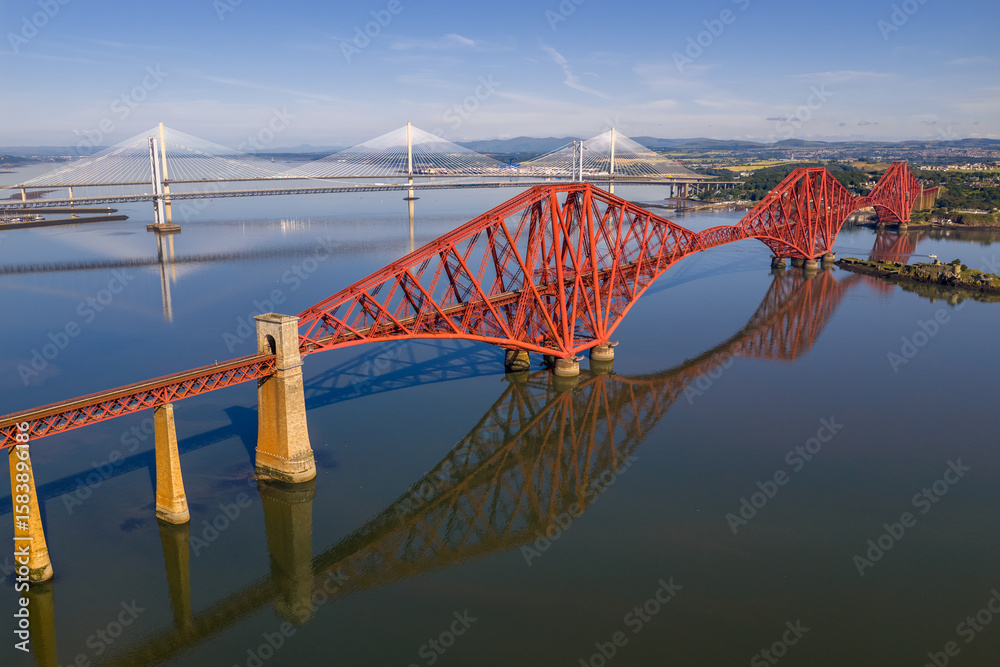 Fototapeta premium Aerial image featuring the Forth bridge with the Forth Road Bridge and Queensferry crossing Bridge on the background. Edinburgh - Scotland. 