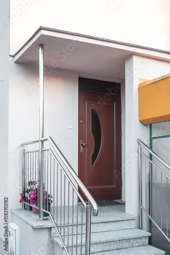 Inviting front entrance with a grand wooden door, stone accents, and decorative plants displayed. Facade of a modern building with modern doors. Designer entrance door to country house. Modern design.