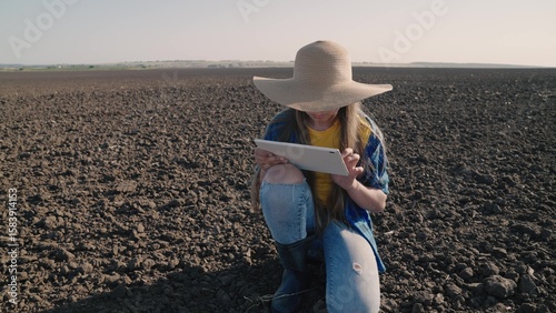 Fotografie Agriculture, an agronomist with a tablet checks in the field fertile land, organ