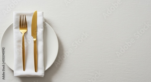 Elegant gold cutlery placed on white napkin and plate  
