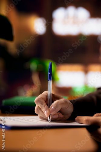 Cuadro en lienzo Mature college student completing class notes on printed papers, writing important information in a study room under green lamp