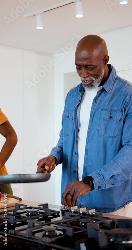 Vertical video: African American father and son in kitchen igniting stove chopping tomato
