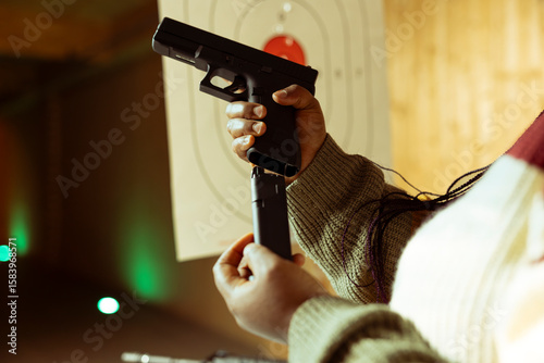 Photography Close up of person reloading magazine into pistol during firearm practice session at indoor shooting range, learning safety practices