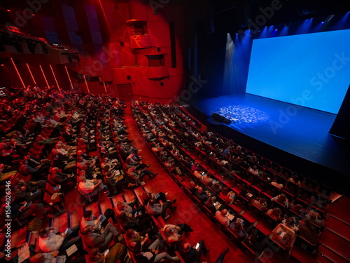 Foto Theater auditorium interior with red seats and dramatic blue stage lighting show