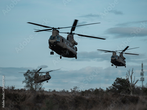 Obraz na plátně Multiple Chinook helicopters flying in formation over rural terrain with communi