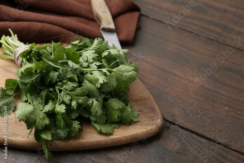 Billede på lærred Cutting board with fresh cilantro and knife on wooden table, closeup