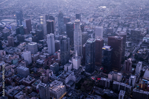 Aerial twilight view of downtown Los Angeles skyline with skyscrapers and modern office buildings rising above the urban sprawl in soft blue light