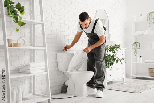 Male plumber repairing toil...