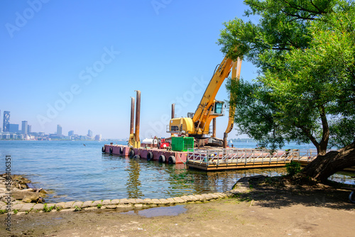 marine construction barge with heavy equipment working near shore on a big city harbour shot inToronto in summer 