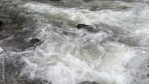 Clear mountain river water flows swiftly between large rocks, top view. Clear mountain river water. The water flows in waves. Splash of river water. Natural river views in the countryside.