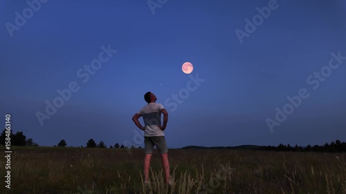 Amateur astronomer watching stars, Moon, planets and other celestial objects from a field in nature.
