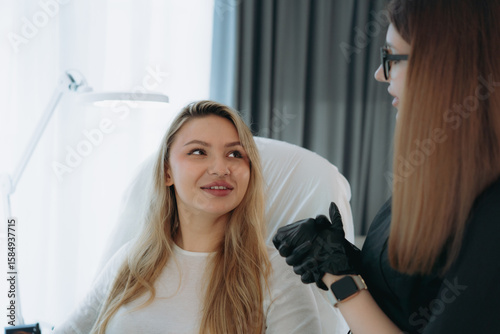 woman before facian rejuvenation injection at aesthetic clinic . Doctor explains procedure