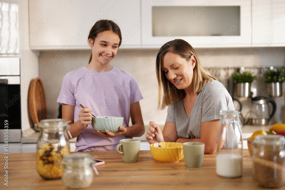 A mother and daughter enjoy breakfast together in a sunny kitchen, with bowls of cereal and cups of coffee. Laughter and warmth fill the air as they bond over their meal. A mother and daughter enjoy breakfast together in a sunny kitchen, with bowls of cereal and cups of coffee. Laughter and warmth fill the air as they bond over their meal.