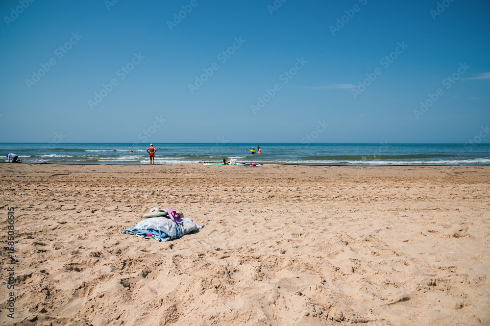 a towel and flip-flops are lying on the sandy beach a towel and flip-flops are lying on the sandy beach