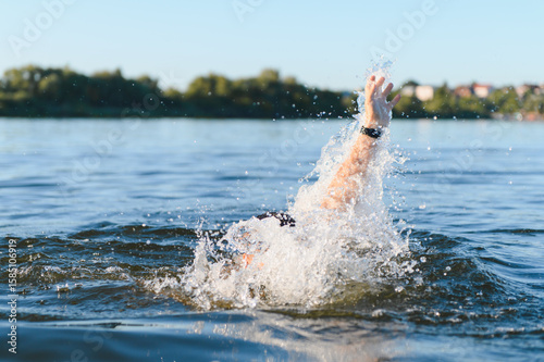 Fotografie Man drowning in a lake raising hand asking for help