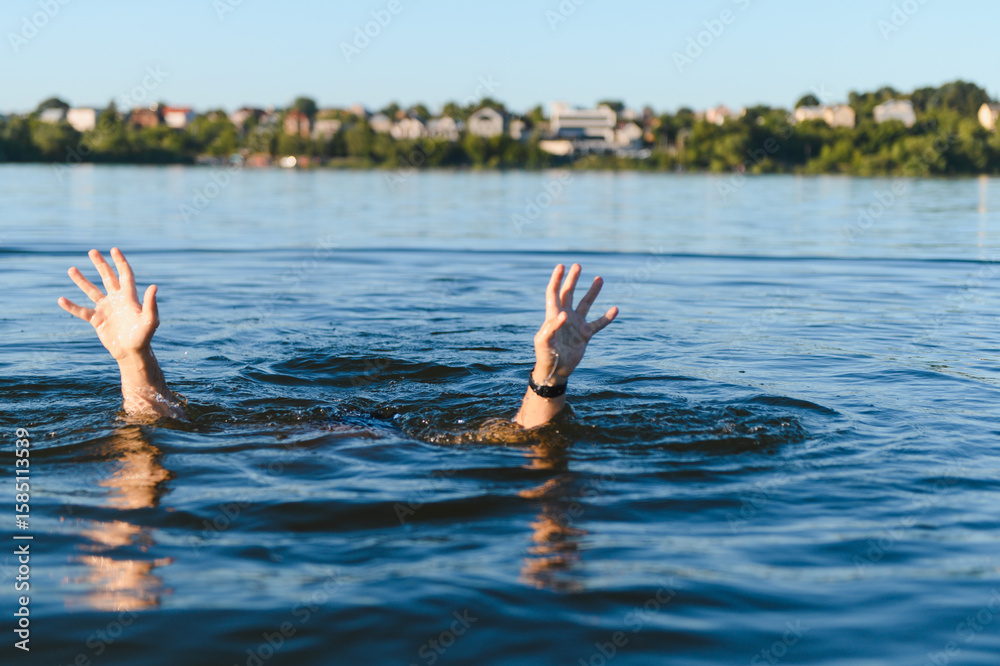 Fototapeta premium Man drowning in water raising hands asking for help