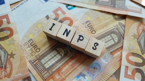 INPS acronym made of wooden letter cubes on pile of Euro banknotes. Istituto Nazionale della Previdenza Sociale (National Institute of Social Security)