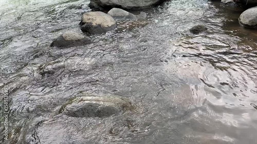 Clear and clean river water splashes swiftly between the rocks. The fast flow of river water. The splash of river water creates a peaceful atmosphere. The surface of the river water is clear.