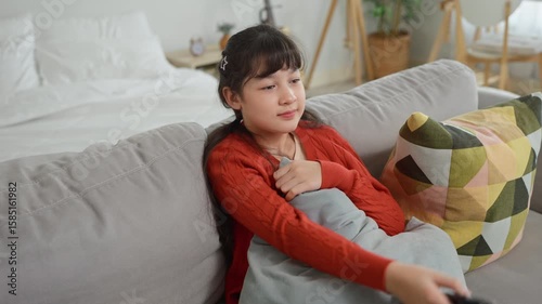 Asian young girl sitting on sofa and watching TV in living room at home. 