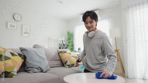 Asian young handsome man cleaning indoors in cozy room at home. 